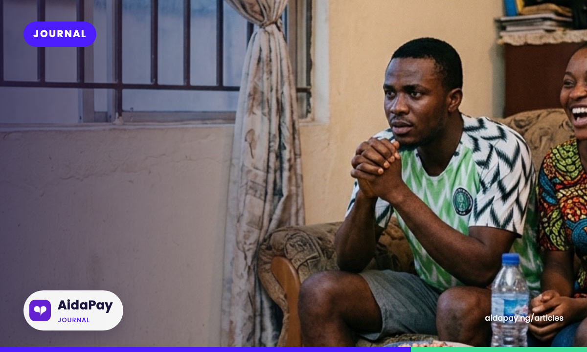 Friends reacting to a football match on TV together in a Nigerian living room at dusk