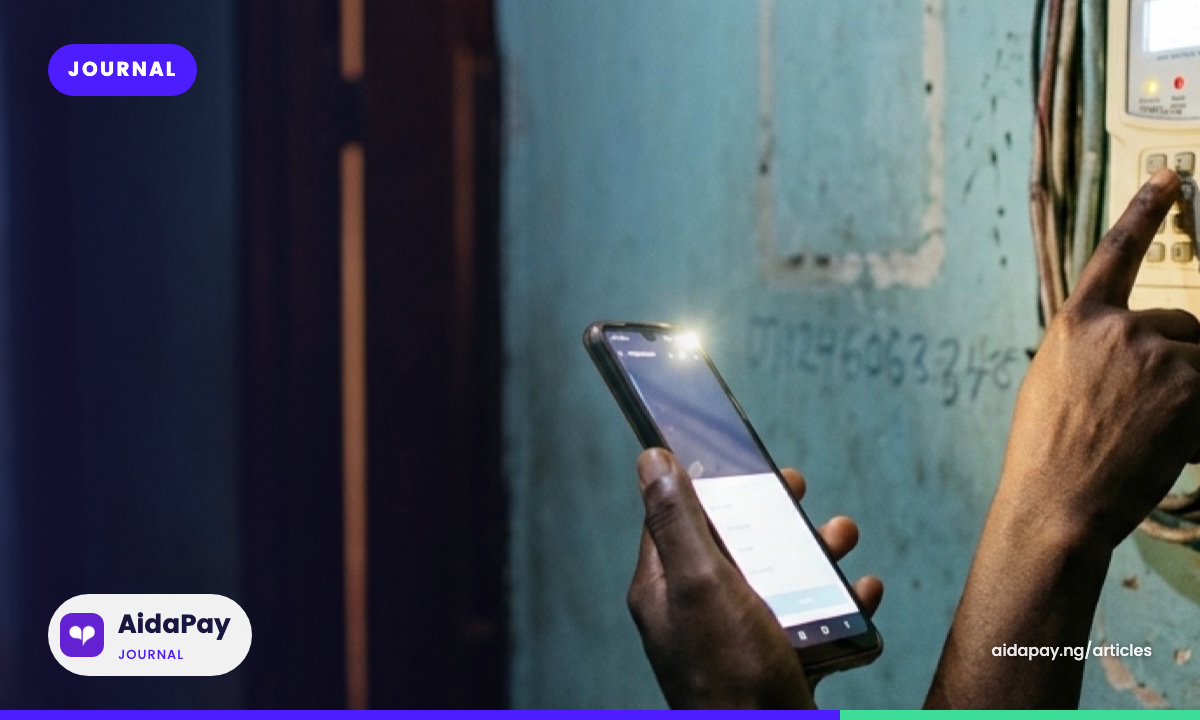 A hand carefully types a Key Change Token into a prepaid meter keypad by phone torchlight at night