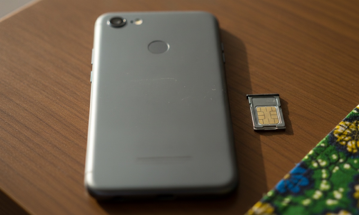 A smartphone and SIM card on a table, representing buying mobile data to stream football in Nigeria.