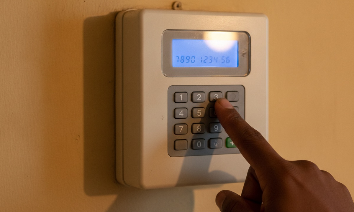Close-up of a hand entering a code into a prepaid electricity meter keypad